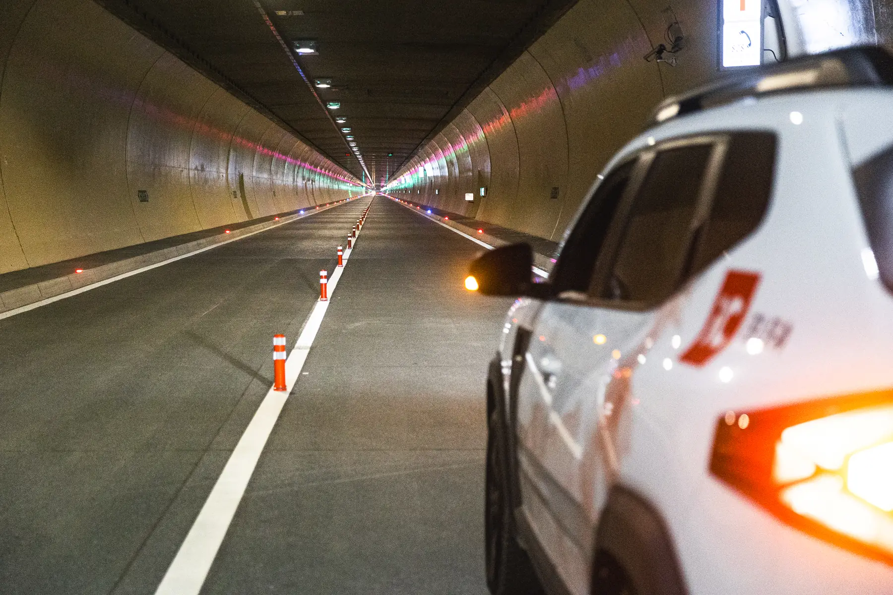 Inside a motorway tunnel tube, lit and marked out, seen from beside a maintenance vehicle